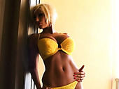 Short haired blond haired bimbo poses in her yellow bikini in doorjamb