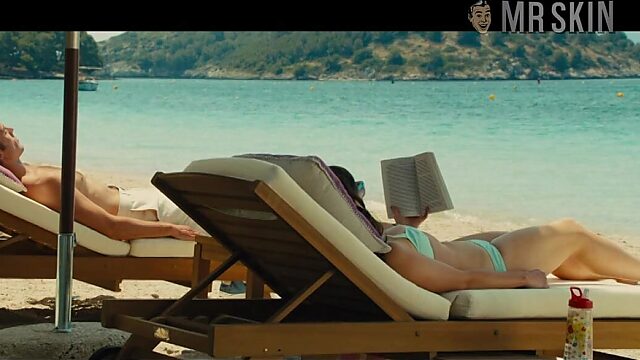 Emilia Clarke in swim suit is sunbathing by the poolside